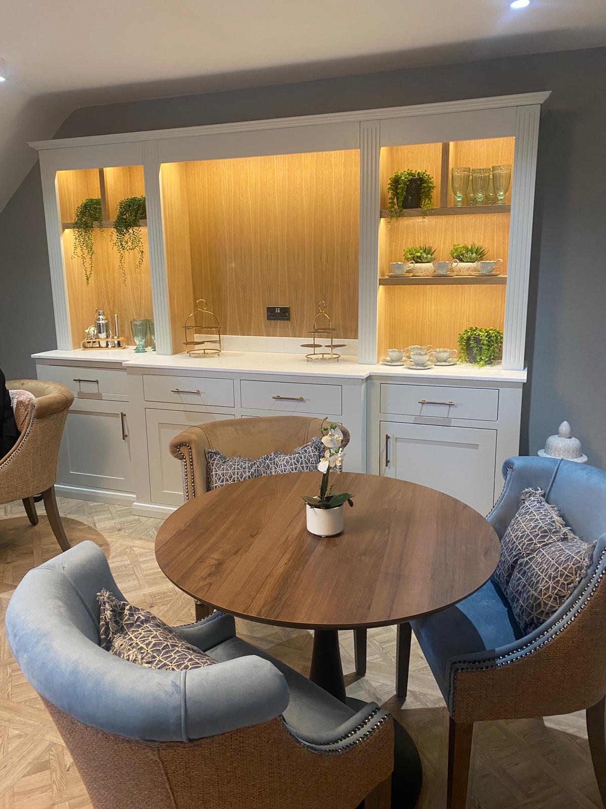The new café lounge area at Meadowbrook Manor care home in Garforth, Leeds, showing elegant upholstered seating and warm illuminated display cabinetry