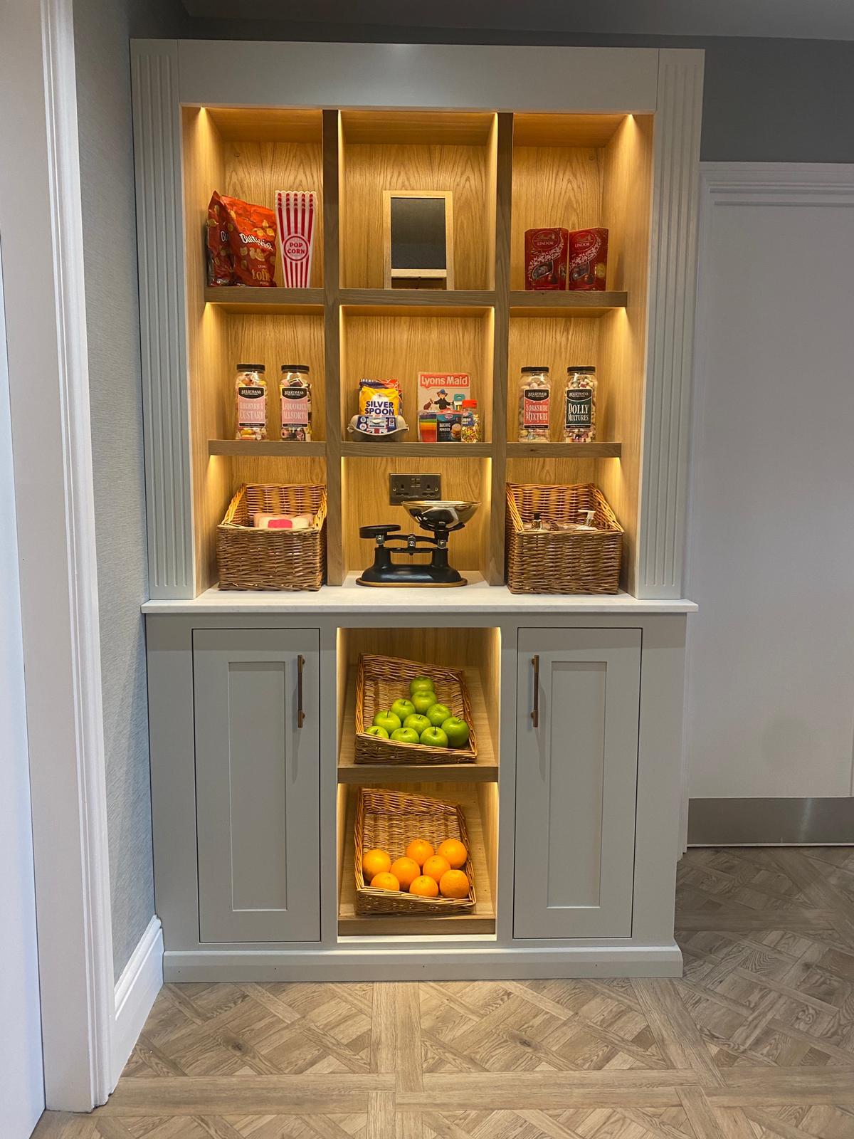 The café counter area at Meadowbrook Manor care home showing marble worktop, copper-handled cabinetry and illuminated shelving with plants and glassware