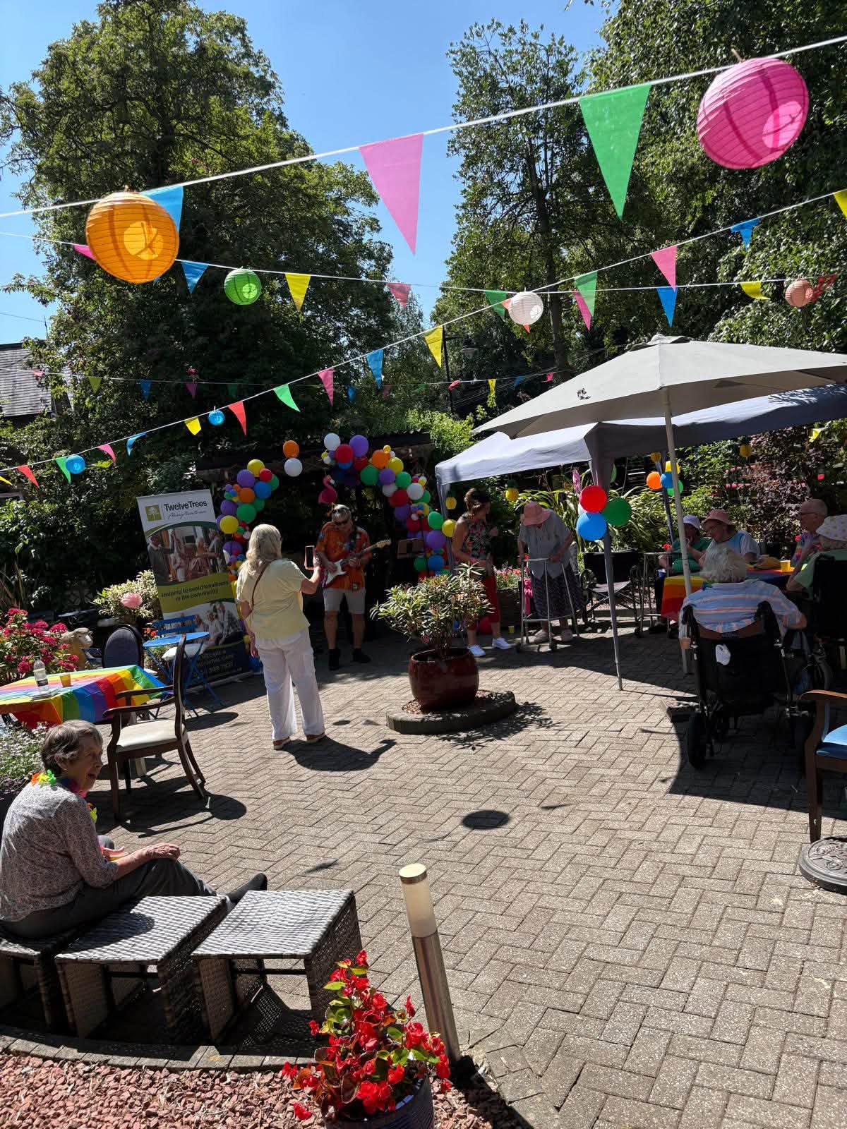 Residents at the Caribbean summer fayre under the sun canopy at Twelve Trees Care Home Sheffield